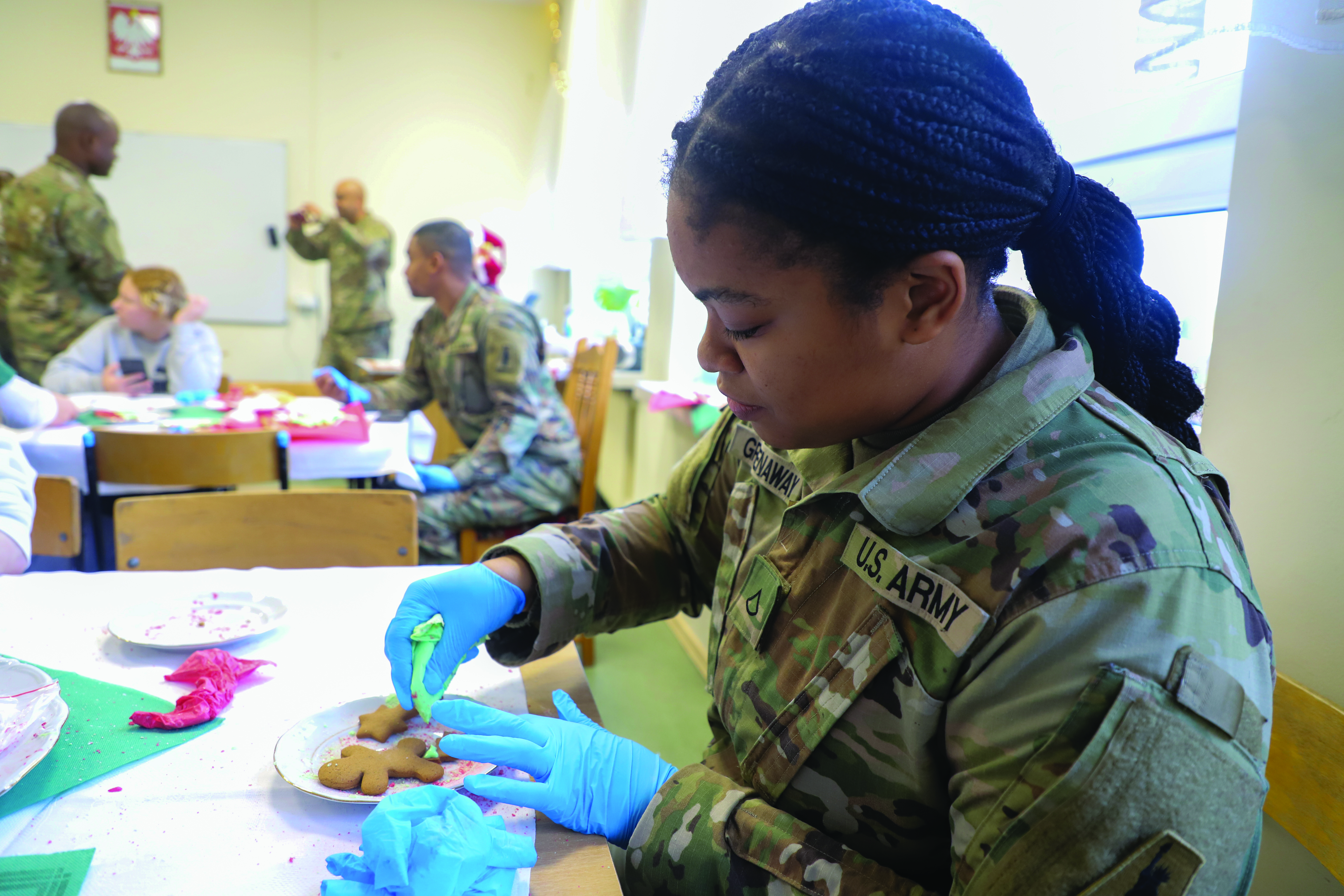 PFC Jashonique Greenaway, a paralegal specialist assigned to the 436th Movement Control Battalion, decorates cookies during a community holiday event at a local school in Witkowo, Poland, on 11 December 2023. (Credit: SPC Elsi Delgado)